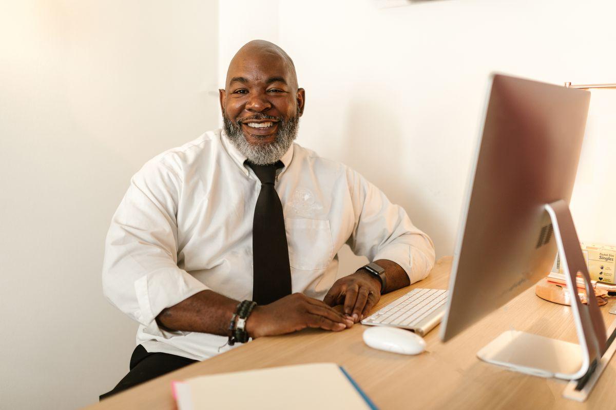 A smiling school administrator at a desk with a computer
